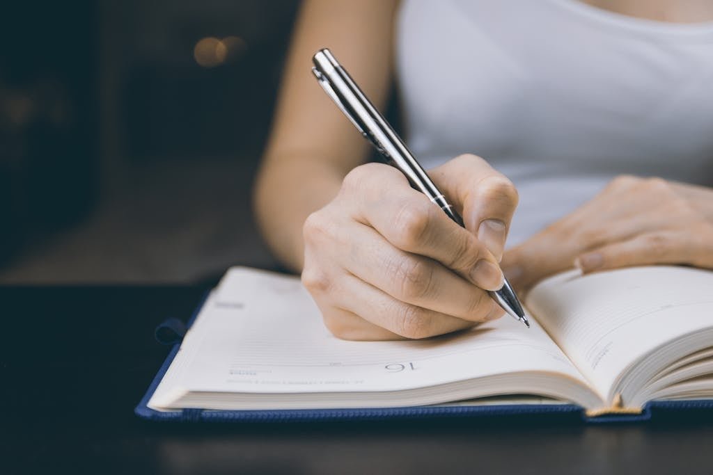 Person Writing on Notebook - Improve your writing