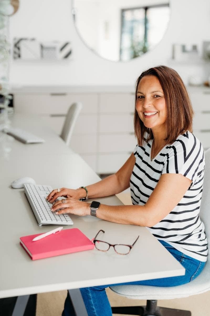 Emma-Louise Smith sitting at a desk smiling at the camera